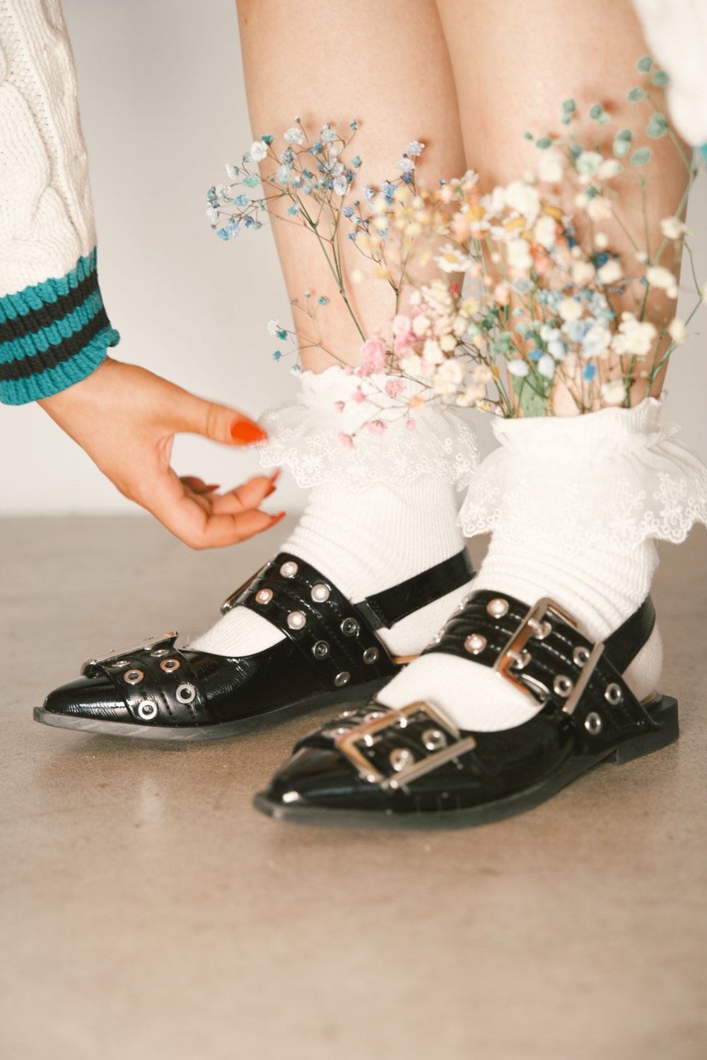 A hand reaching past flower-trimmed socks and mary janes