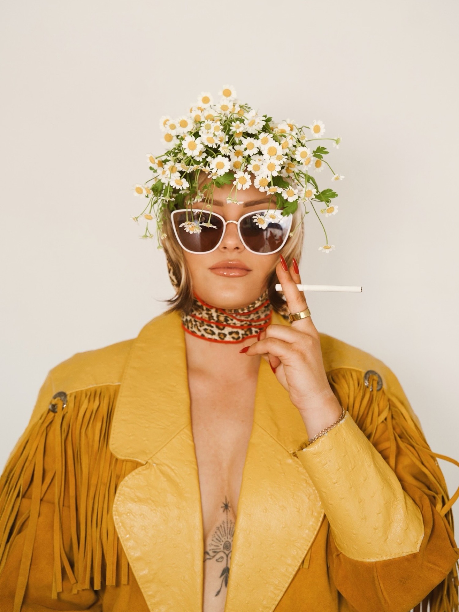Corey Earl in a daisy crown, white sunglasses and a marigold jacket