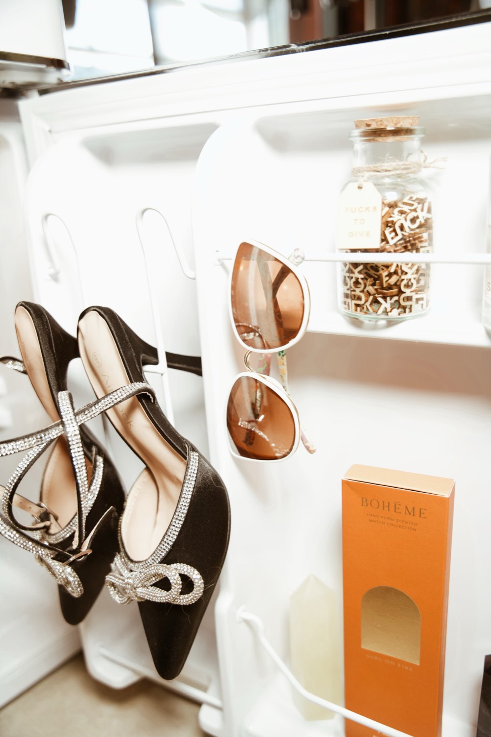 Heels, sunglasses and products on a white shelf