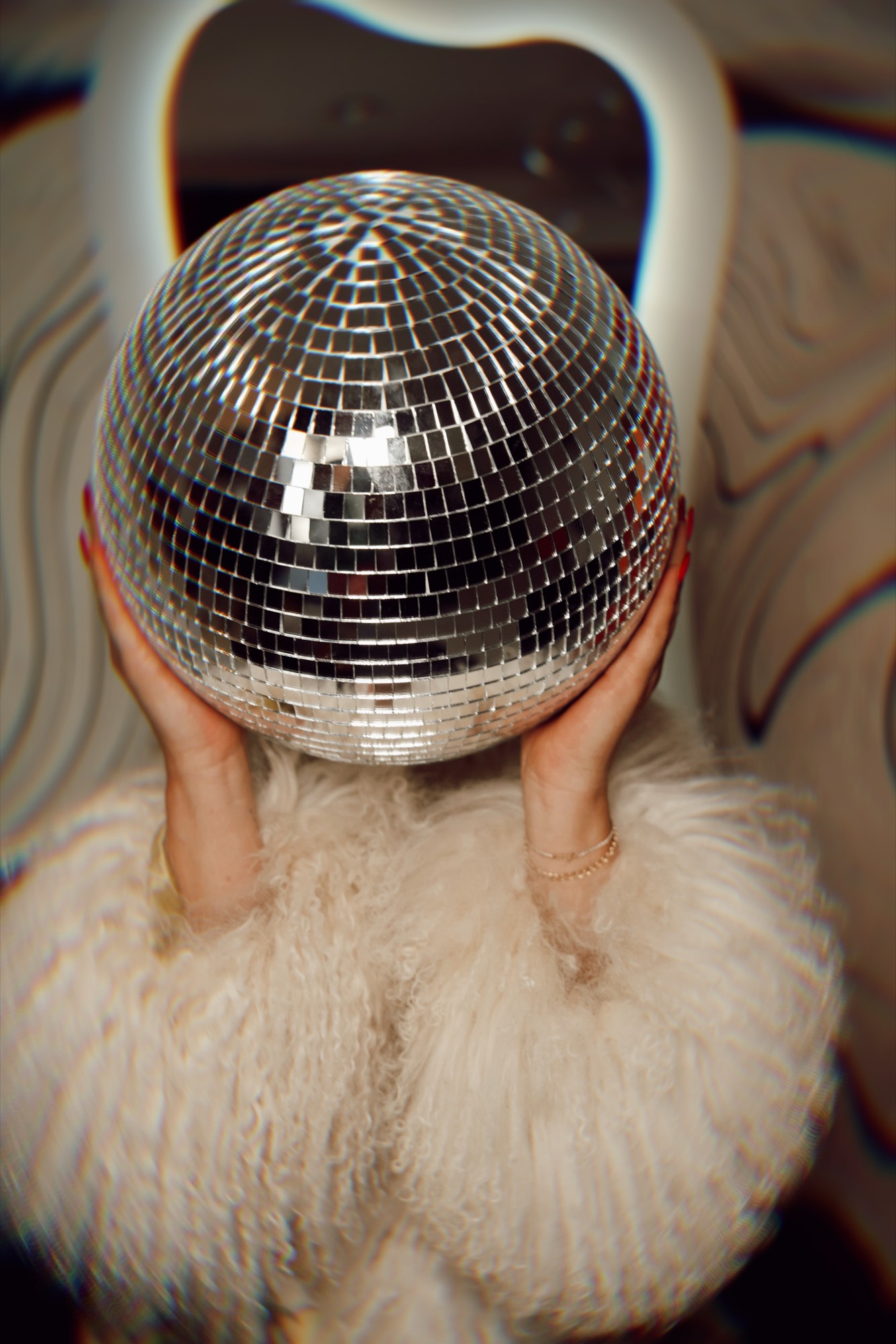 A mirrorball held up against a white fur coat