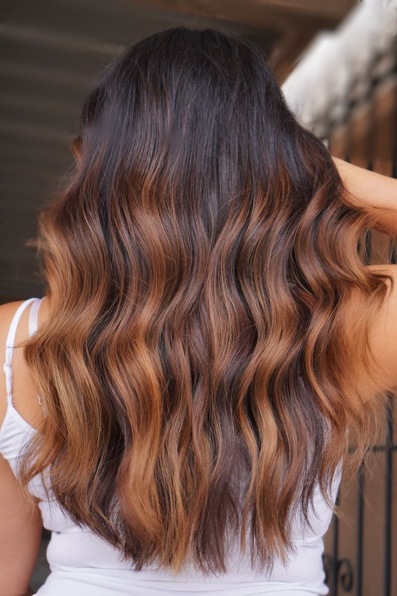 Copper balayage through dark hair, from the back